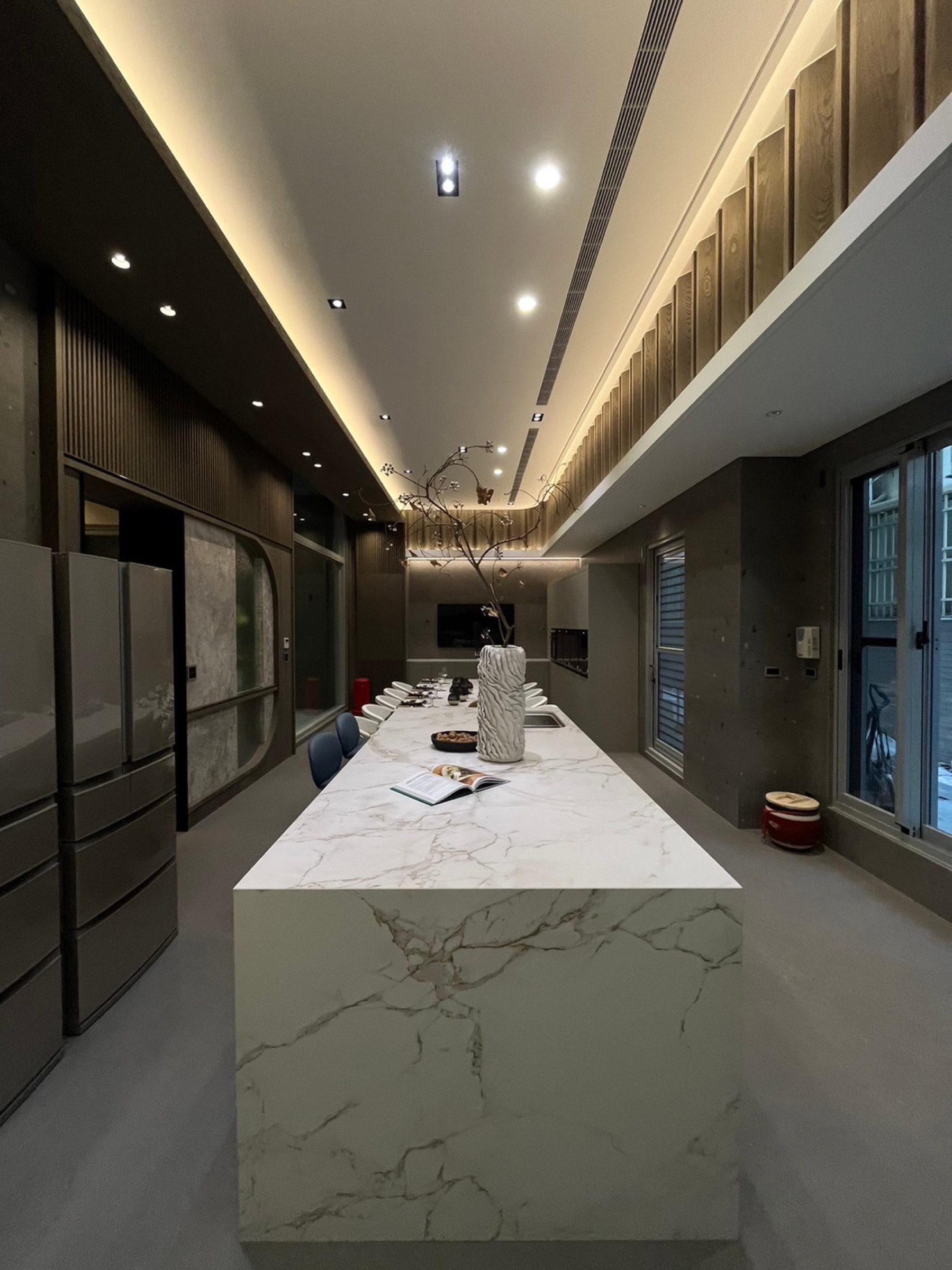 奢華住宅長中島縱深視角,大理石紋檯面與間接照明天花